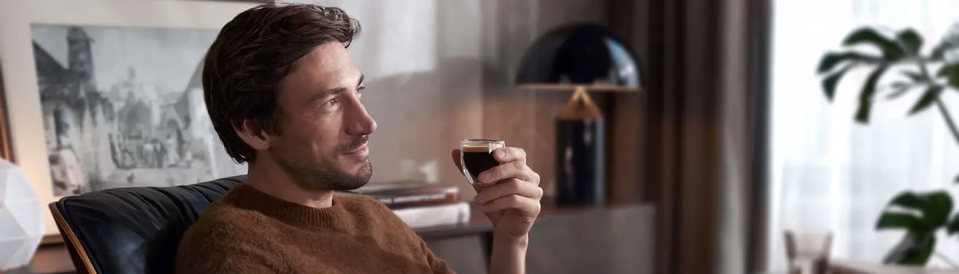 Un homme boit une boisson au café parfaitement préparée, assis dans un fauteuil confortable. Un homme boit une boisson au café parfaitement préparée, assis dans un fauteuil confortable.