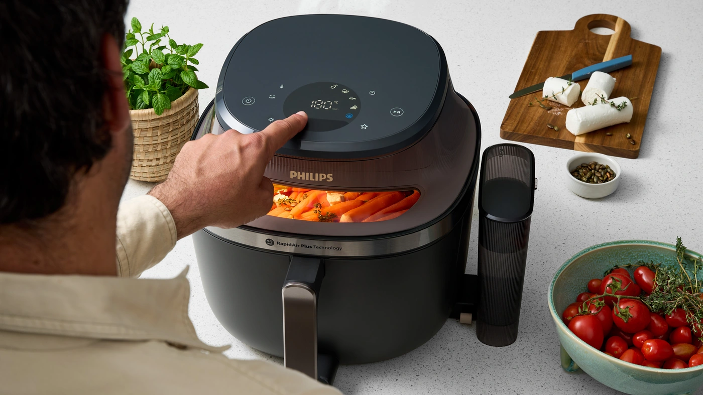 Philips Airfryer with cooking window and RapidAir technology in a modern kitchen, cooking golden-brown chicken drumsticks with a sleek black and gold design. Philips Airfryer with cooking window and RapidAir technology in a modern kitchen, cooking golden-brown chicken drumsticks with a sleek black and gold design.