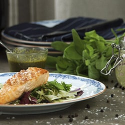 Laksemiddag på en seng av salat med saus ved siden av; i en vakker tallerken og stilfulle omgivelser. Laksemiddag på en seng av salat med saus ved siden av; i en vakker tallerken og stilfulle omgivelser.