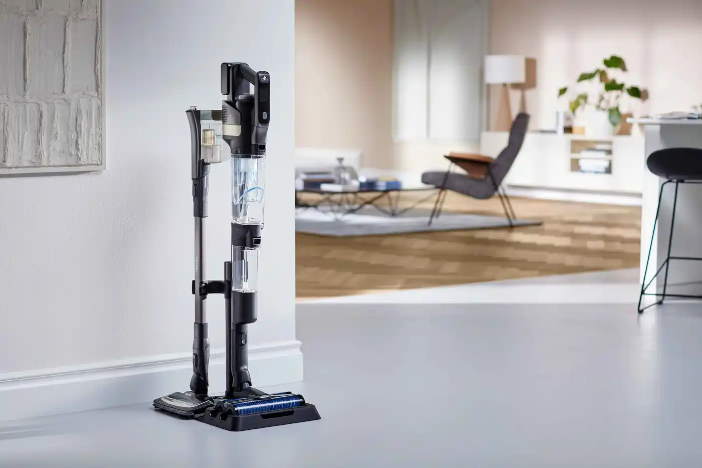 Sistema de aspiradora sin cable Philips AquaTrio 9000 en su base de carga. Diseño elegante y modular para limpieza versátil de suelos, se integra perfectamente en un hogar moderno. Sistema de aspiradora sin cable Philips AquaTrio 9000 en su base de carga. Diseño elegante y modular para limpieza versátil de suelos, se integra perfectamente en un hogar moderno.