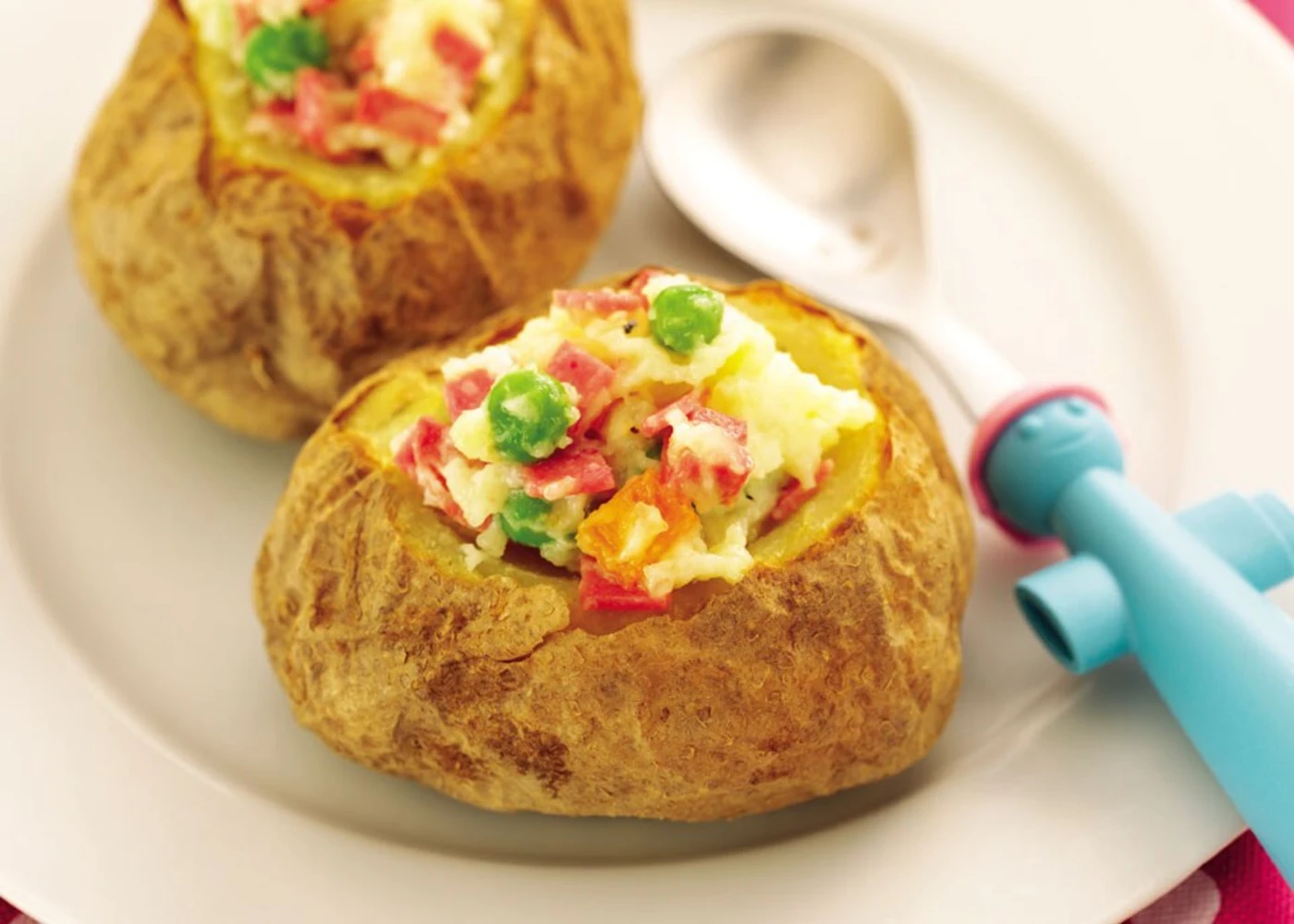 Two baked potatoes topped with green peas and red pepper, served on a white plate Two baked potatoes topped with green peas and red pepper, served on a white plate