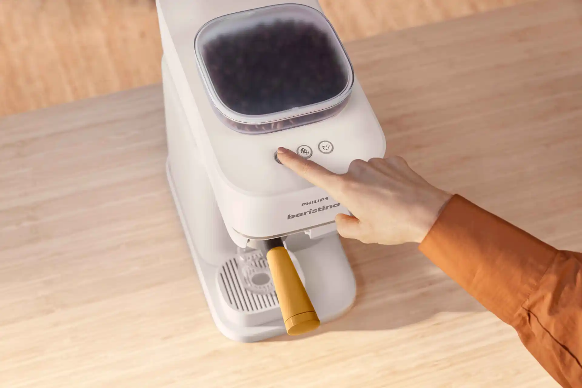Hand die startknop indrukt op Philips Baristina koffiemachine met hele bonen. Ervaar premium koffie van boon tot kop met dit Baristina apparaat op een licht houten oppervlak. Hand die startknop indrukt op Philips Baristina koffiemachine met hele bonen. Ervaar premium koffie van boon tot kop met dit Baristina apparaat op een licht houten oppervlak.