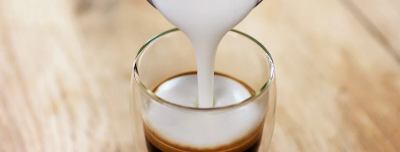 Spienione mleko jest nalewane do szklanki Spienione mleko jest nalewane do szklanki