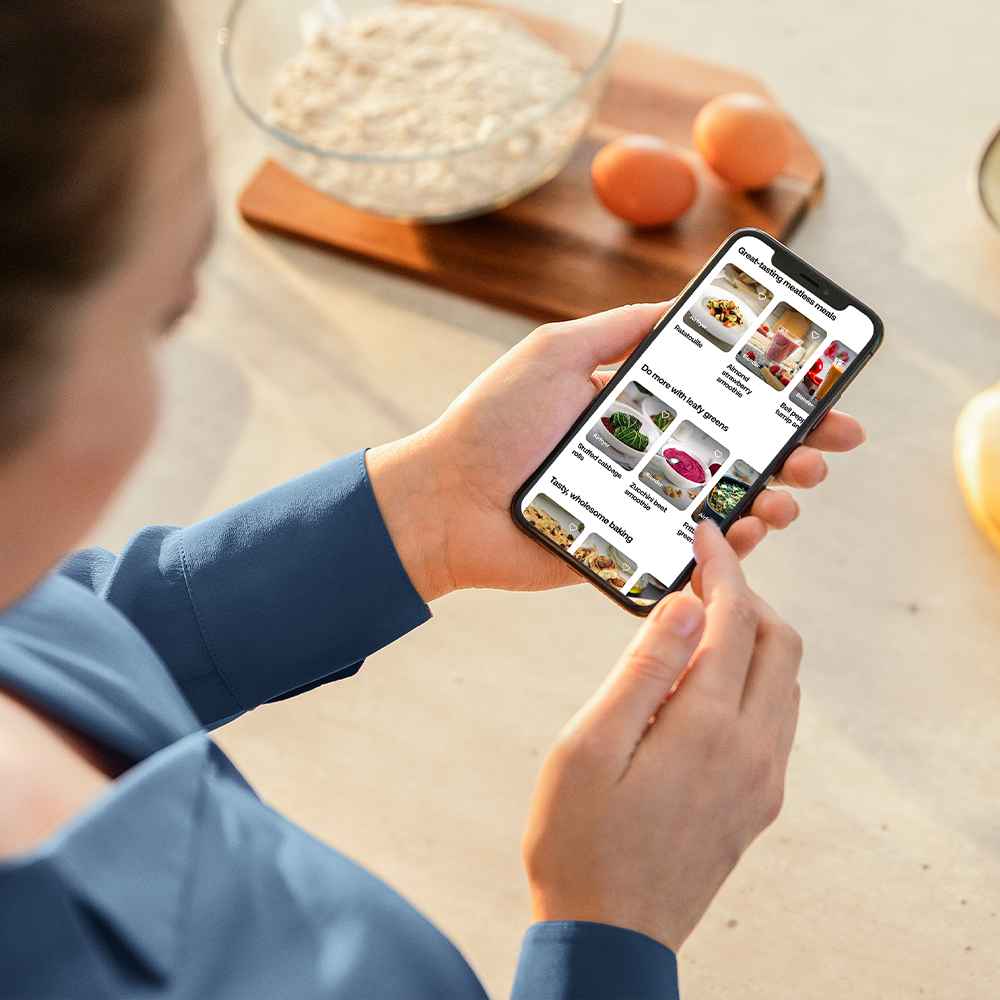 Kvinne som bruker Philips Blend & Juice-appen for oppskrifter på smarttelefonen sin. Blending & Juicing tilbyr kreative måter å bruke Philips kjøkkenprodukter på. Kvinne som bruker Philips Blend & Juice-appen for oppskrifter på smarttelefonen sin. Blending & Juicing tilbyr kreative måter å bruke Philips kjøkkenprodukter på.
