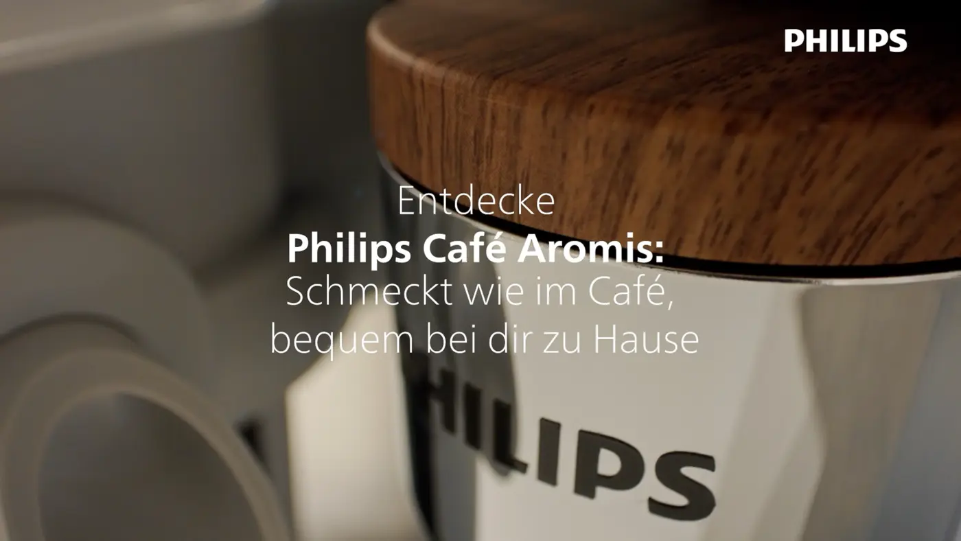 Nahaufnahme der vollautomatischen Philips 8000 LatteGo Pro Café Aromis Espressomaschine mit Holzfinish und Philips-Logo, die Kaffee in Café-Qualität bewirbt. Nahaufnahme der vollautomatischen Philips 8000 LatteGo Pro Café Aromis Espressomaschine mit Holzfinish und Philips-Logo, die Kaffee in Café-Qualität bewirbt.