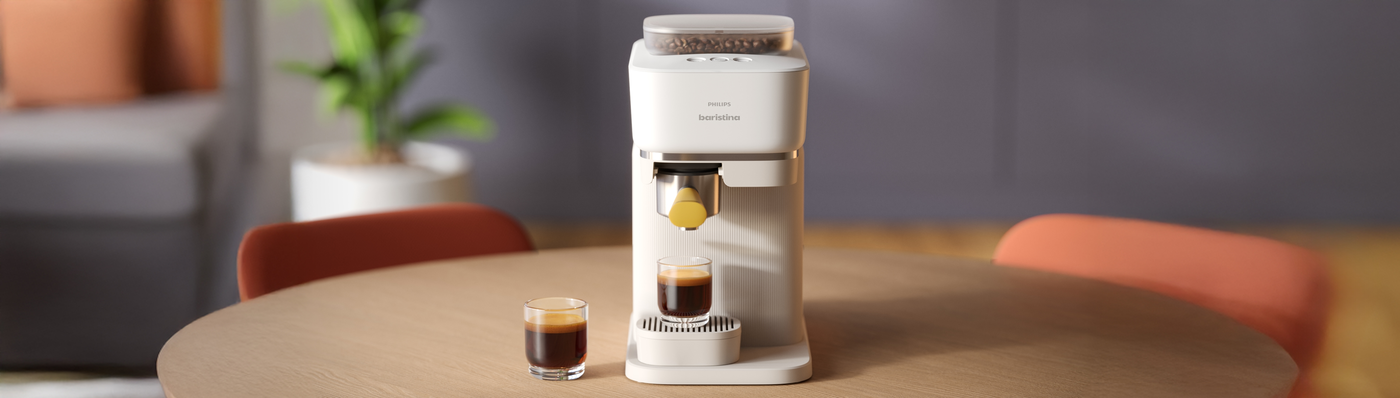 Philips Baristina coffee machine brewing a fresh espresso on a wooden table. Philips Baristina coffee machine brewing a fresh espresso on a wooden table.