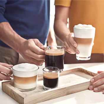 Nærbilde som viser resultatet fra Philips kaffemaskin: latte, espresso og svart kaffe presentert på et trebrett midt i en sosial sammenkomst. Nærbilde som viser resultatet fra Philips kaffemaskin: latte, espresso og svart kaffe presentert på et trebrett midt i en sosial sammenkomst.