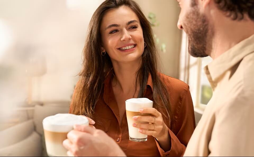 Ein Mann und eine Frau halten Kaffeetassen in der Hand und lächeln sich an. Ein Mann und eine Frau halten Kaffeetassen in der Hand und lächeln sich an.