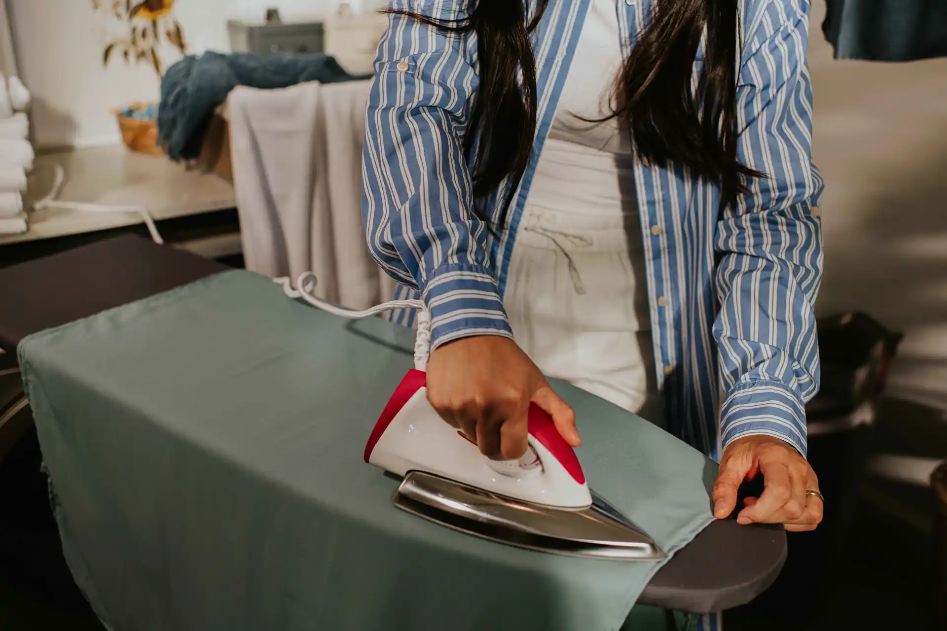 Close-up of a person using a Philips dry iron on a garment in a home laundry setting. Close-up of a person using a Philips dry iron on a garment in a home laundry setting.