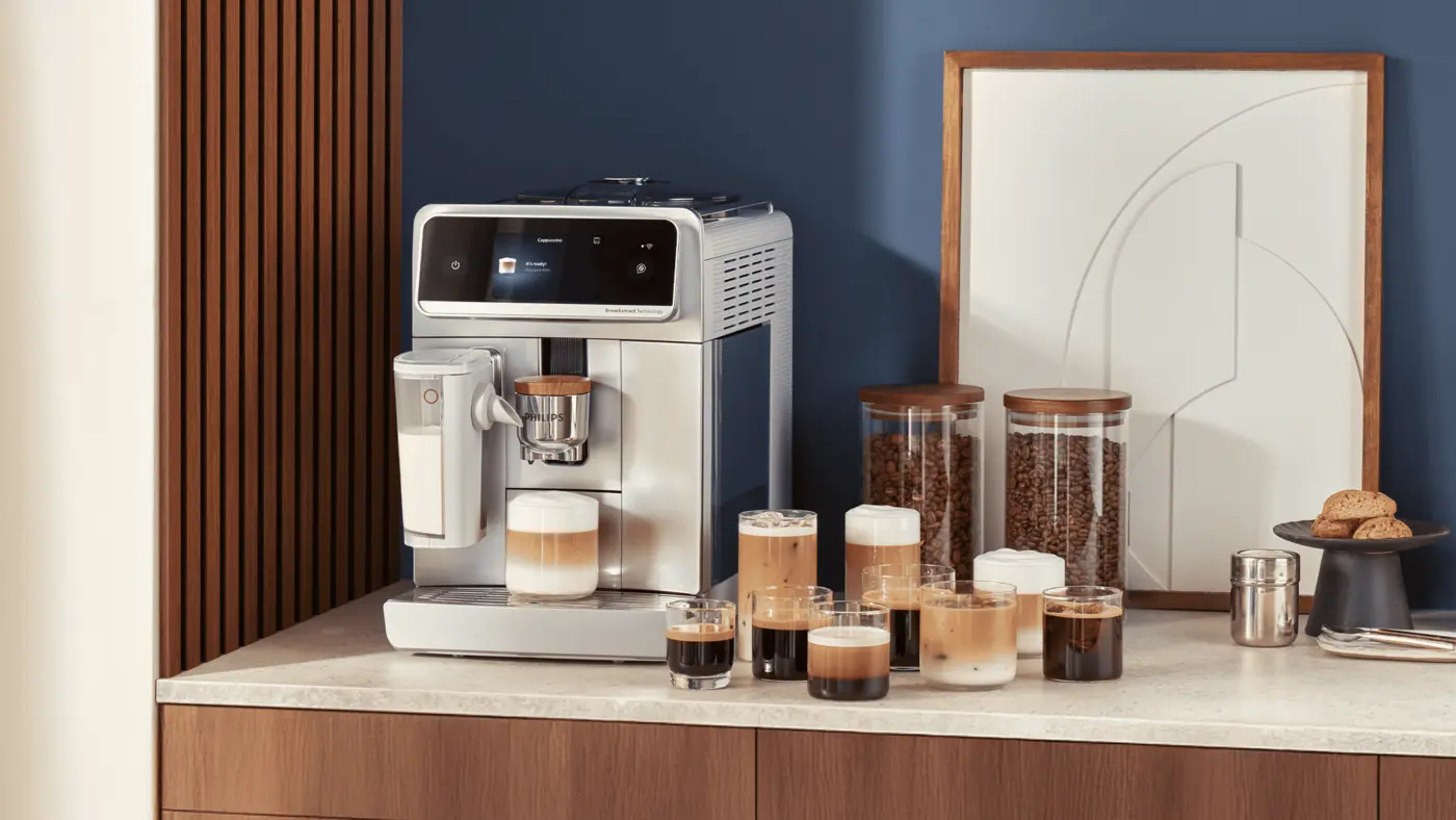 Una cafetera espresso automática Philips en una encimera de cocina con varias tazas de café, tarros de granos y una jarra al lado. Una cafetera espresso automática Philips en una encimera de cocina con varias tazas de café, tarros de granos y una jarra al lado.