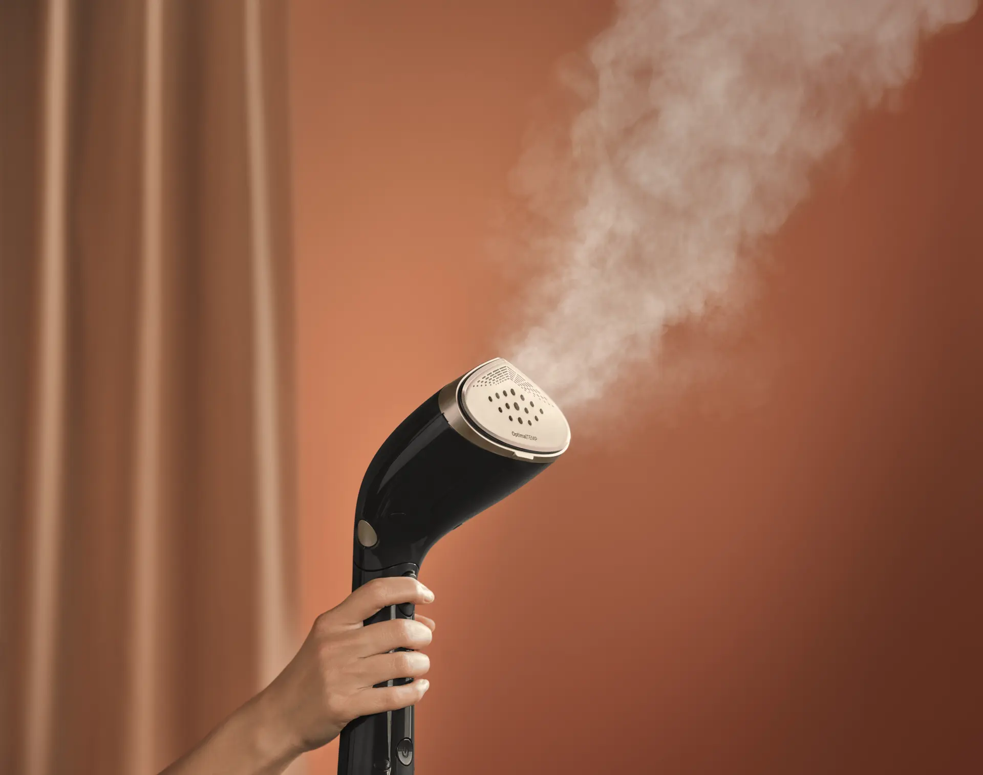 Ręka trzymająca parownicę ręczną Philips, część linii Philips Garment Care, bez wysiłku emitująca parę. Podkreśla czarno-złoty design, uwypuklając innowacyjną pielęgnację odzieży. Ręka trzymająca parownicę ręczną Philips, część linii Philips Garment Care, bez wysiłku emitująca parę. Podkreśla czarno-złoty design, uwypuklając innowacyjną pielęgnację odzieży.