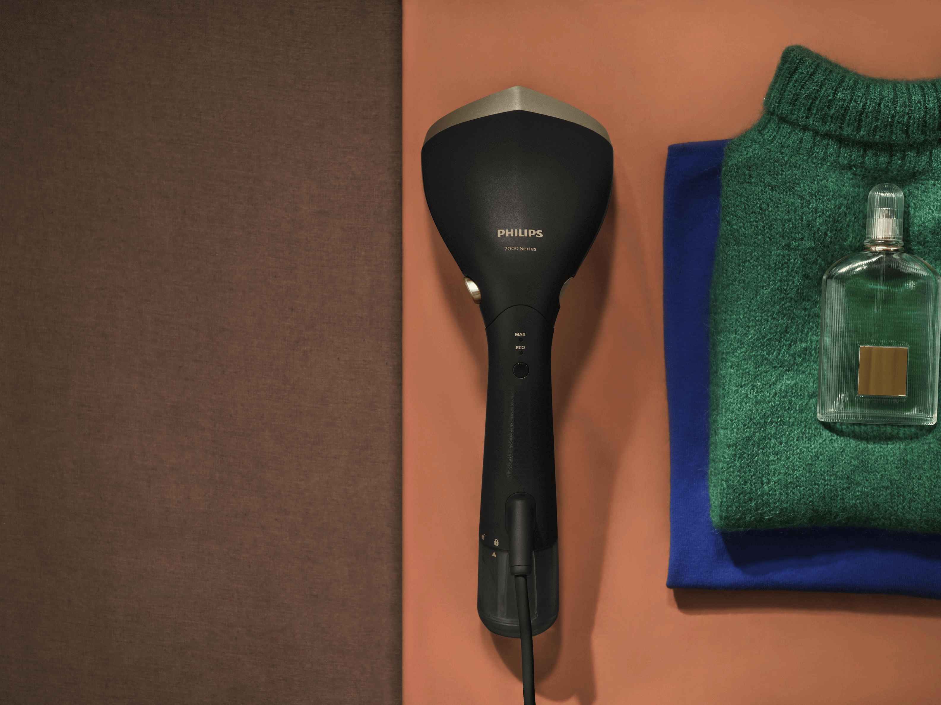Philips kädessä pidettävät höyrystimet: Philips 7000 -sarjan vaatehöyrystin studiossa, esitellen MAX/ECO-höyrytystasot taitettujen neuleiden vieressä. Tyylikäs muotoilu. Philips kädessä pidettävät höyrystimet: Philips 7000 -sarjan vaatehöyrystin studiossa, esitellen MAX/ECO-höyrytystasot taitettujen neuleiden vieressä. Tyylikäs muotoilu.