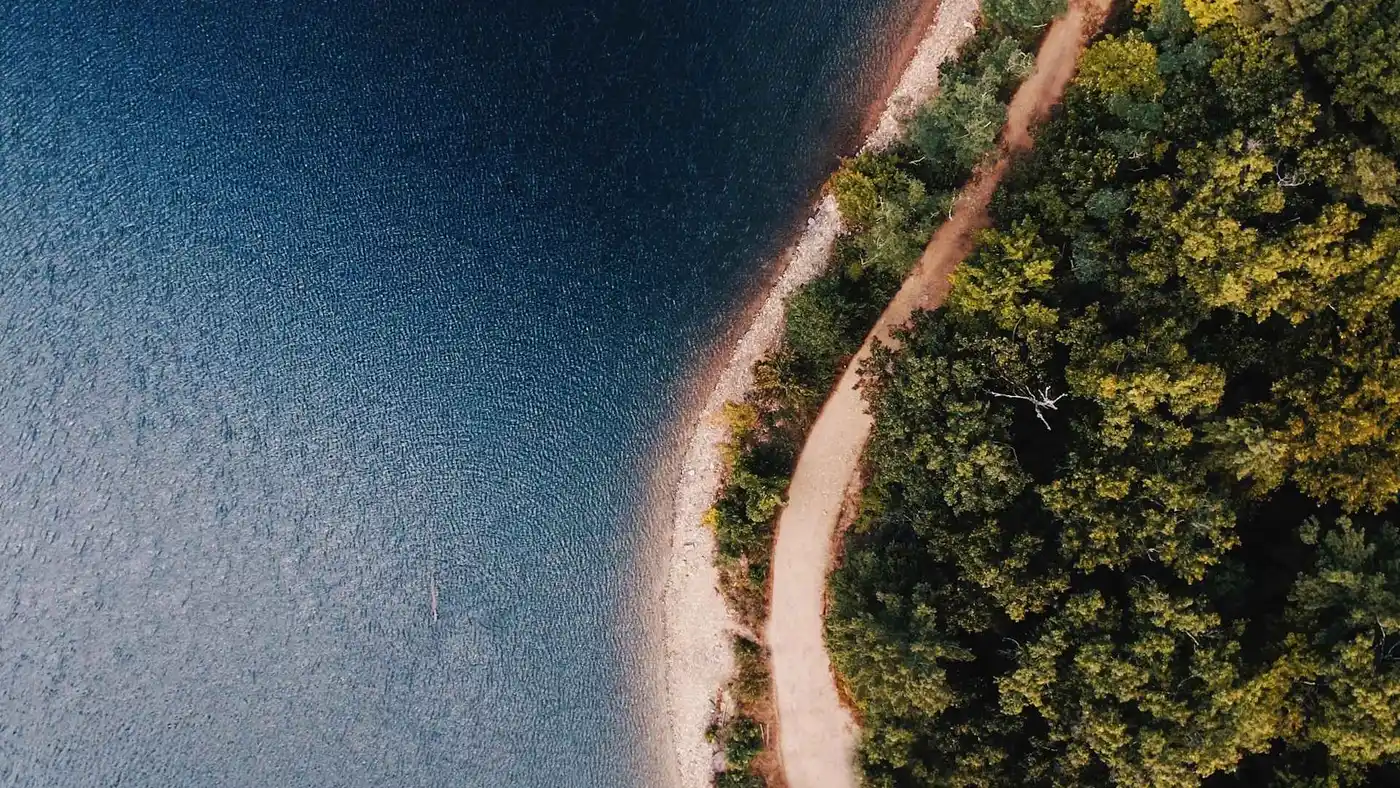 Luftbild: ruhiges Seeufer, Pfad, Wald; erkunden Sie Natur mit klarem, immersivem Klang & robuster Qualität von Philips Portable Audio. Luftbild: ruhiges Seeufer, Pfad, Wald; erkunden Sie Natur mit klarem, immersivem Klang & robuster Qualität von Philips Portable Audio.