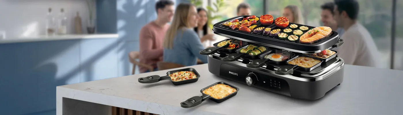 Philips elektrisk grill med glaslåg, hvor der grilles bøffer og grøntsager på køkkenbordet. Indendørs grillning ved høj temperatur giver saftigt kød, grillede grøntsager og hverdagsmåltider til hele familien. Philips elektrisk grill med glaslåg, hvor der grilles bøffer og grøntsager på køkkenbordet. Indendørs grillning ved høj temperatur giver saftigt kød, grillede grøntsager og hverdagsmåltider til hele familien.
