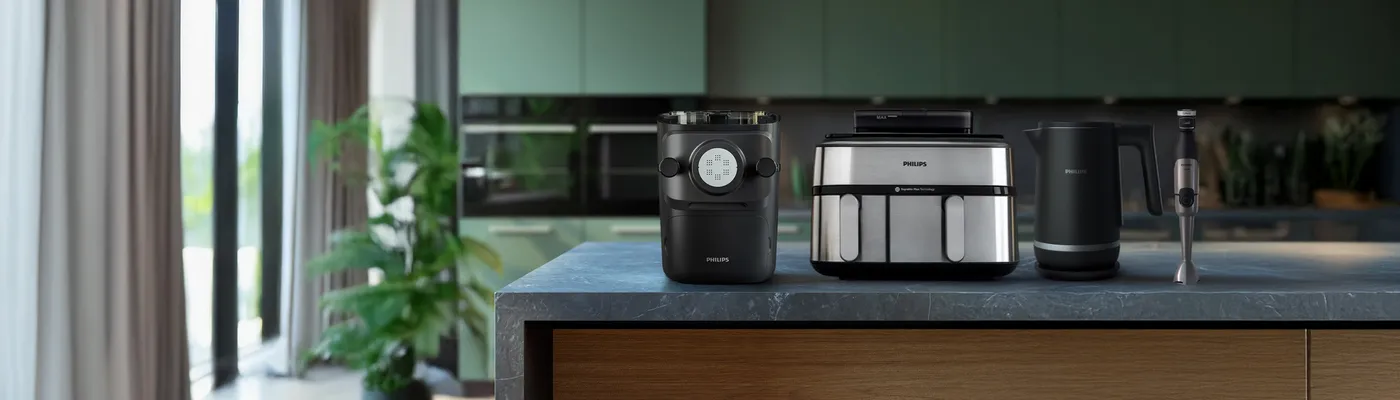 Philips Pastamaschine, Airfryer, Wasserkocher und Stabmixer auf einer modernen Küchenarbeitsplatte ausgestellt. Philips Pastamaschine, Airfryer, Wasserkocher und Stabmixer auf einer modernen Küchenarbeitsplatte ausgestellt.