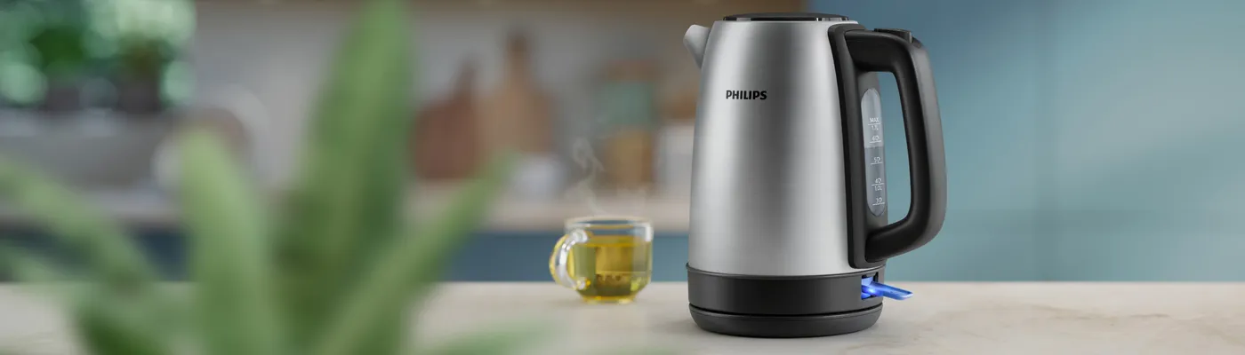 Rychlovarná konvice Philips na kuchyňské lince vedle šálku kouřícího čaje. Rychlovarná konvice Philips na kuchyňské lince vedle šálku kouřícího čaje.