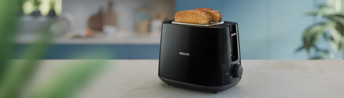 Schwarzer Philips Toaster mit zwei Scheiben geröstetem Brot auf einer Küchenarbeitsplatte. Schwarzer Philips Toaster mit zwei Scheiben geröstetem Brot auf einer Küchenarbeitsplatte.