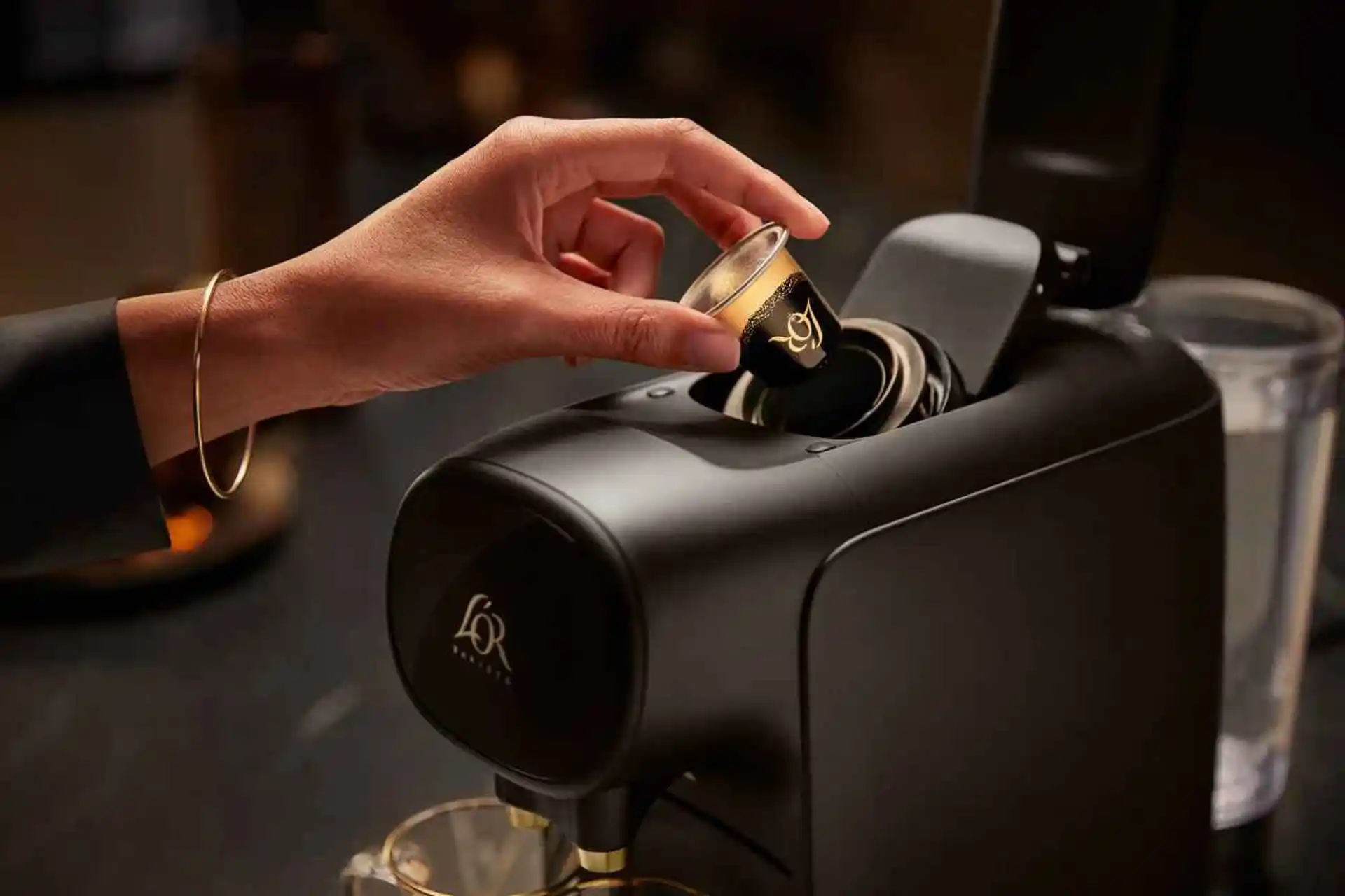 Att manuellt sätta in en Lor-kapsel i en elegant, svart Philips-kaffemaskin och brygga en exceptionell kopp Lor-kaffe. Att manuellt sätta in en Lor-kapsel i en elegant, svart Philips-kaffemaskin och brygga en exceptionell kopp Lor-kaffe.