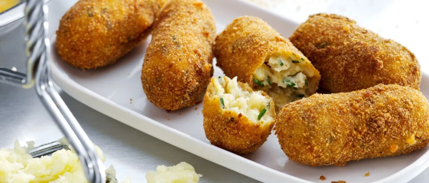 A dish on a plate featuring fried potato croquettes with Parmesan cheese A dish on a plate featuring fried potato croquettes with Parmesan cheese