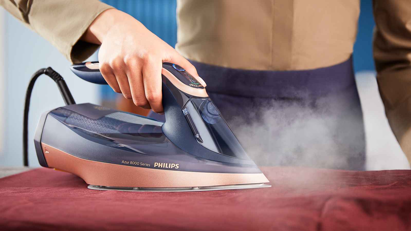 Nærbilde av Philips dampstrykejern med Azur 8000-serien i bruk, glir over et rødt stoff og slipper ut damp. Opplev forskjellen. Nærbilde av Philips dampstrykejern med Azur 8000-serien i bruk, glir over et rødt stoff og slipper ut damp. Opplev forskjellen.