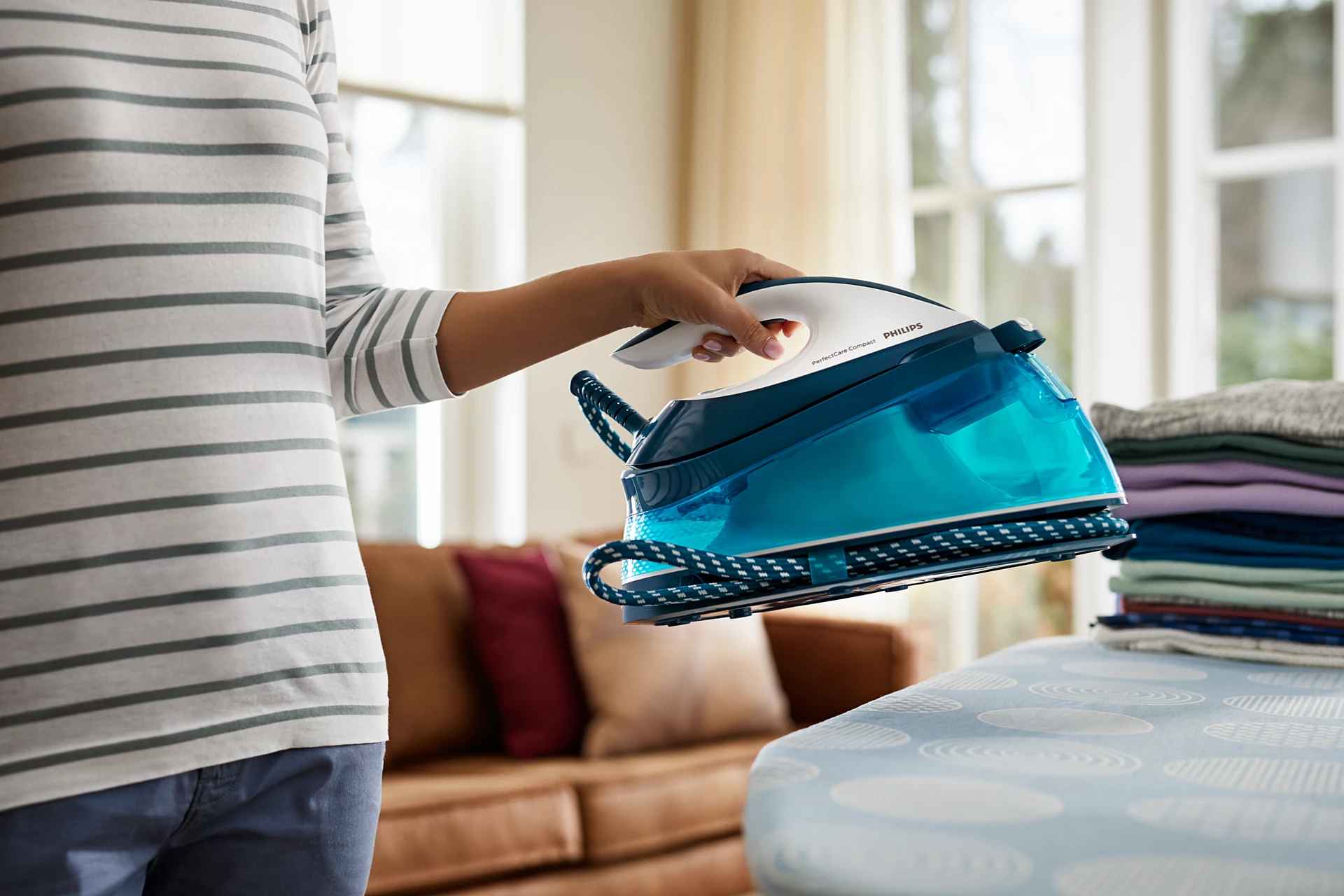 Henkilö pitää Philipsin höyrygeneraattorisilitysrautaa, esitellen optimaalista helppoutta ja tehokkuutta vaatteidenhoidossa. Valmiina tehokkaaseen silitykseen. Henkilö pitää Philipsin höyrygeneraattorisilitysrautaa, esitellen optimaalista helppoutta ja tehokkuutta vaatteidenhoidossa. Valmiina tehokkaaseen silitykseen.