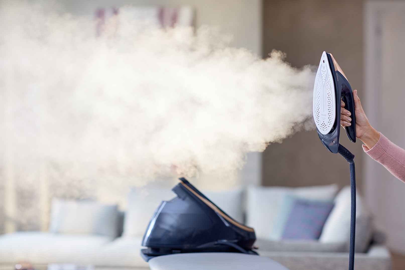 Générateurs vapeur Philips: soin du linge haut de gamme avec une vapeur puissante. L'utilisateur tient le fer avancé, semelle vers l'avant. Base visible; ambiance luxueuse. Générateurs vapeur Philips: soin du linge haut de gamme avec une vapeur puissante. L'utilisateur tient le fer avancé, semelle vers l'avant. Base visible; ambiance luxueuse.