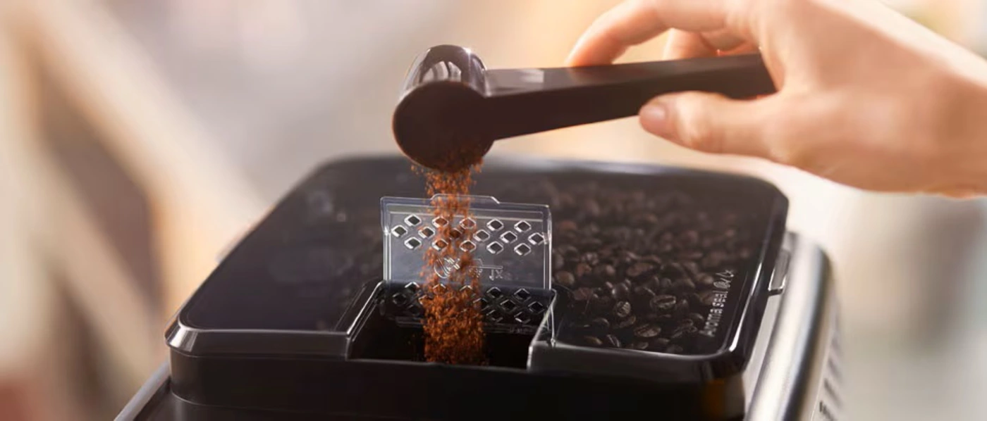 Une personne verse des grains de café dans un moulin à café, se préparant à les moudre pour les infuser. Une personne verse des grains de café dans un moulin à café, se préparant à les moudre pour les infuser.