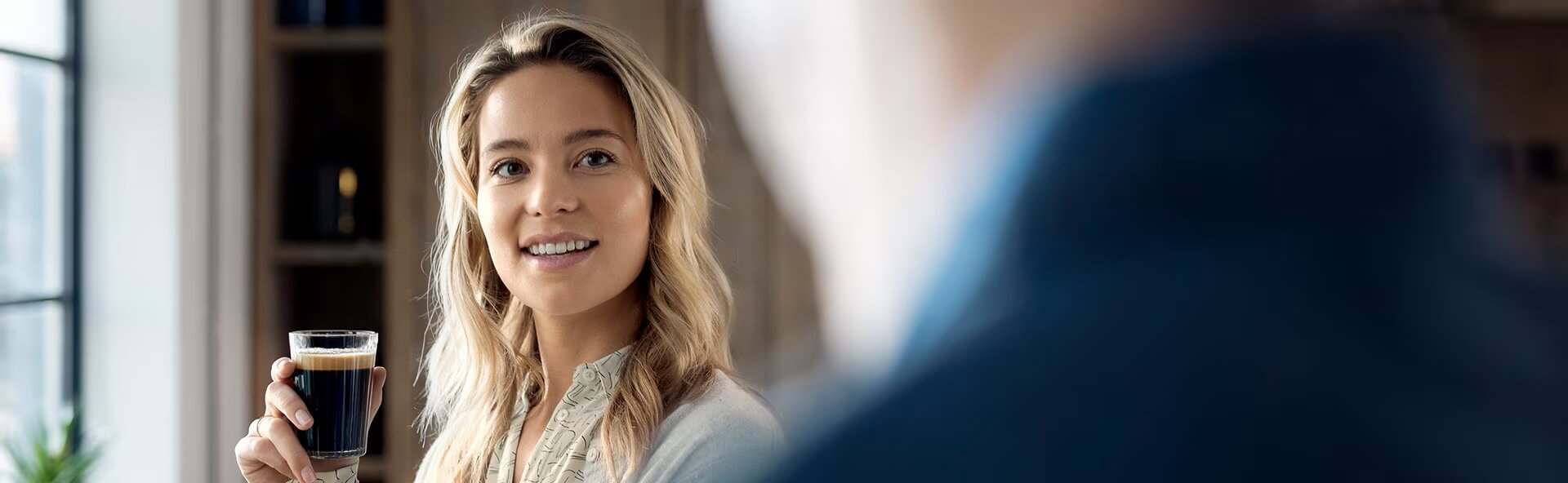 Kobieta uśmiecha się i trzyma filiżankę kawy Kobieta uśmiecha się i trzyma filiżankę kawy