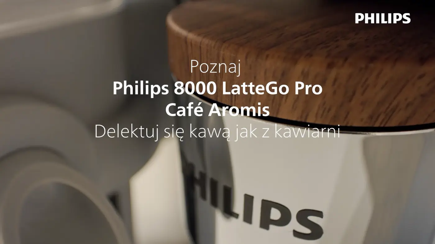 Zbliżenie na w pełni automatyczny ekspres ciśnieniowy Philips 8000 LatteGo Pro Café Aromis z drewnianym wykończeniem i logo Philips, promujące kawę o jakości jak z kawiarni. Zbliżenie na w pełni automatyczny ekspres ciśnieniowy Philips 8000 LatteGo Pro Café Aromis z drewnianym wykończeniem i logo Philips, promujące kawę o jakości jak z kawiarni.